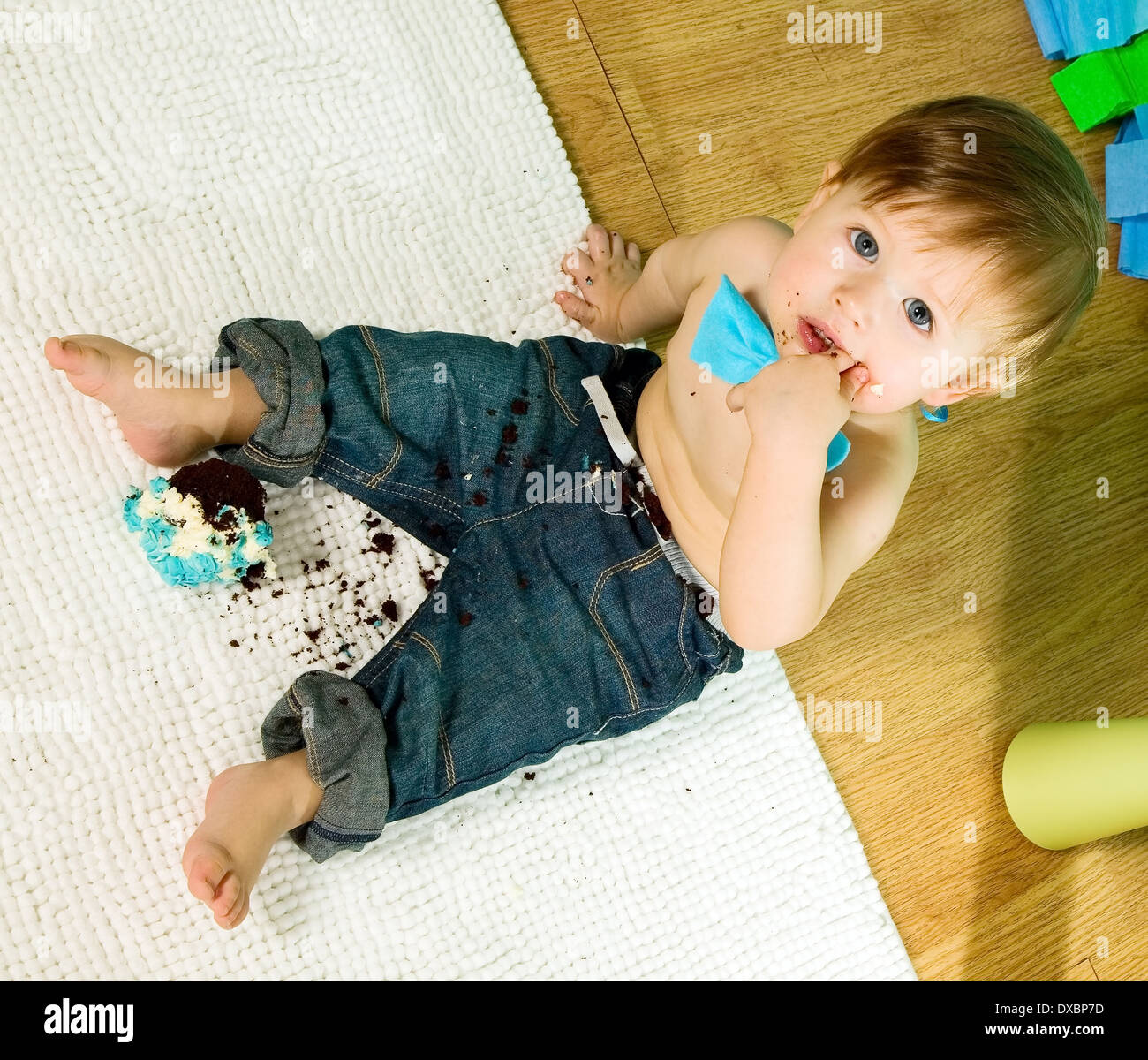 Kind mit blauen Fliege feiert seinen ersten Geburtstag und isst Kuchen Stockfoto