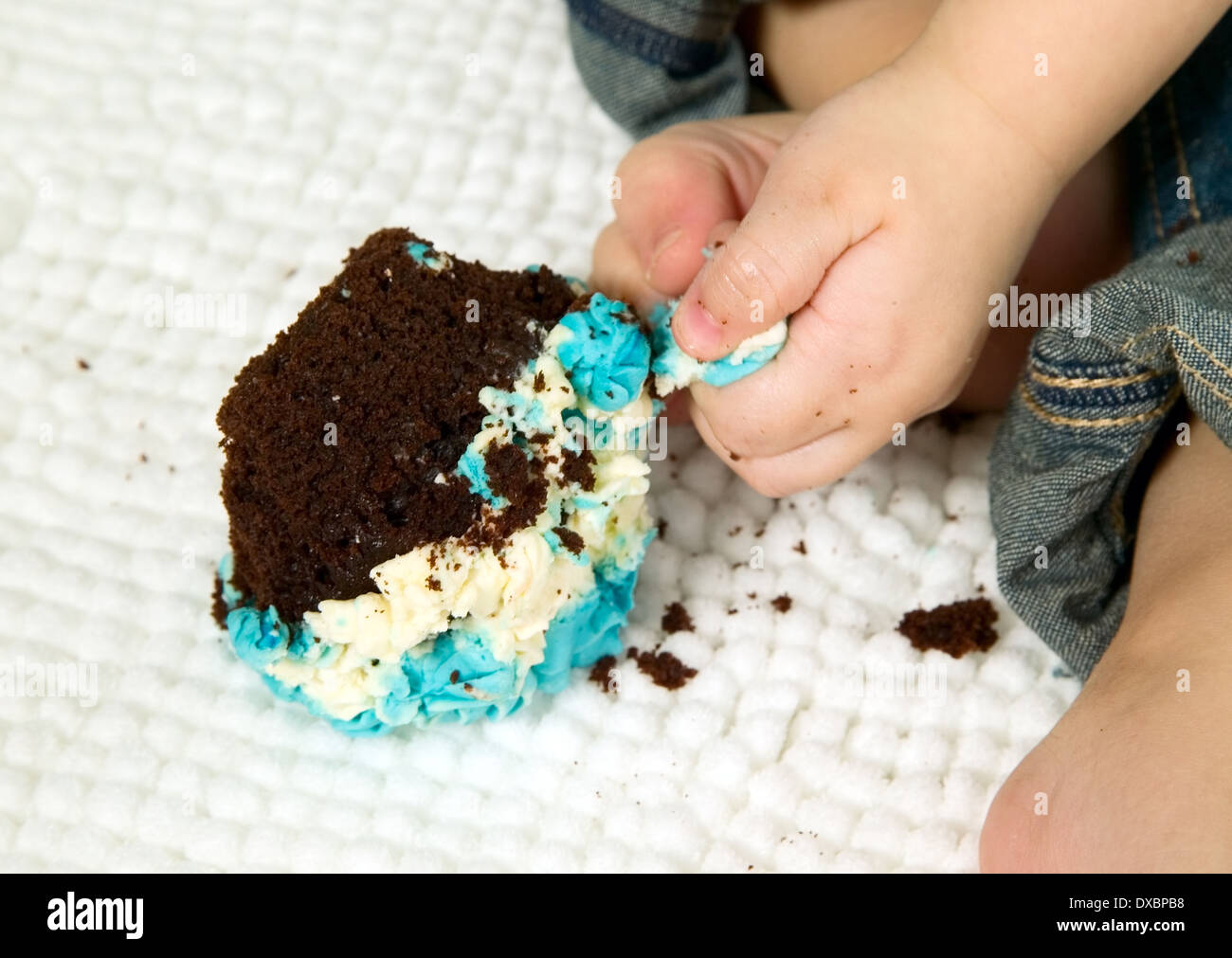 Kind mit blauen Fliege feiert seinen ersten Geburtstag und isst Kuchen Stockfoto