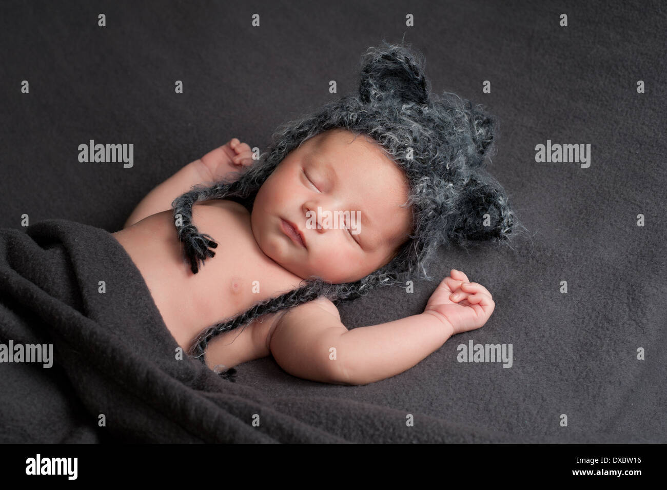 Schlafenden neugeborenen Jungen tragen ein graues gehäkelt-Wolf-Hut. Stockfoto