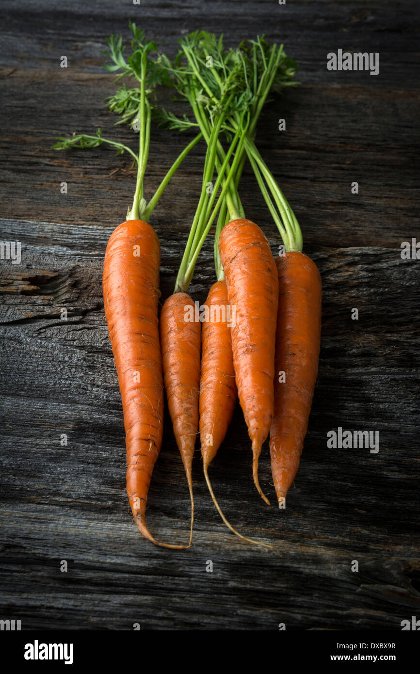 Bio rohe Karotten aus rustikalem Holz mit grünen Stockfoto