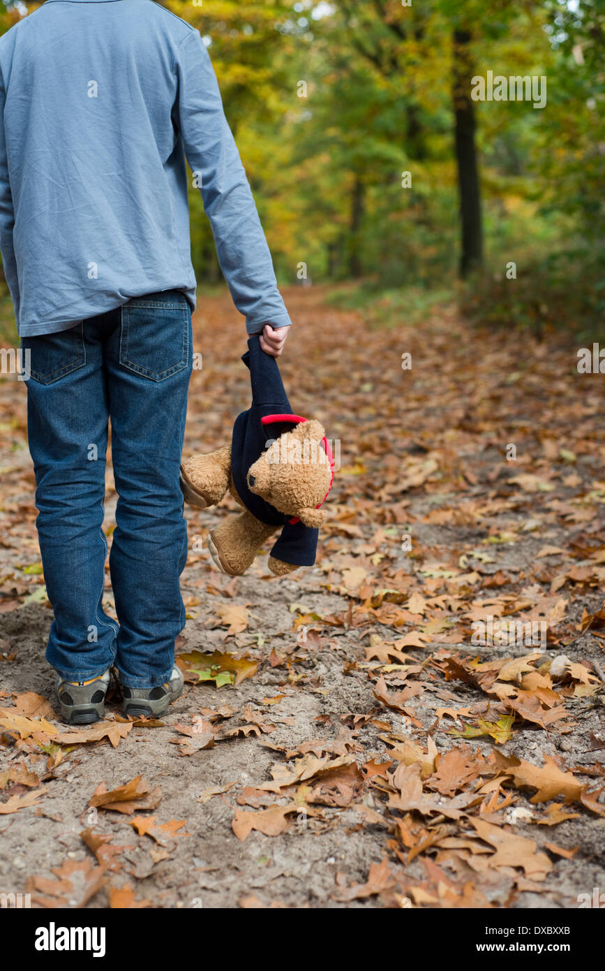 Junge hält einen Teddy Bär für sich allein im Wald Stockfoto