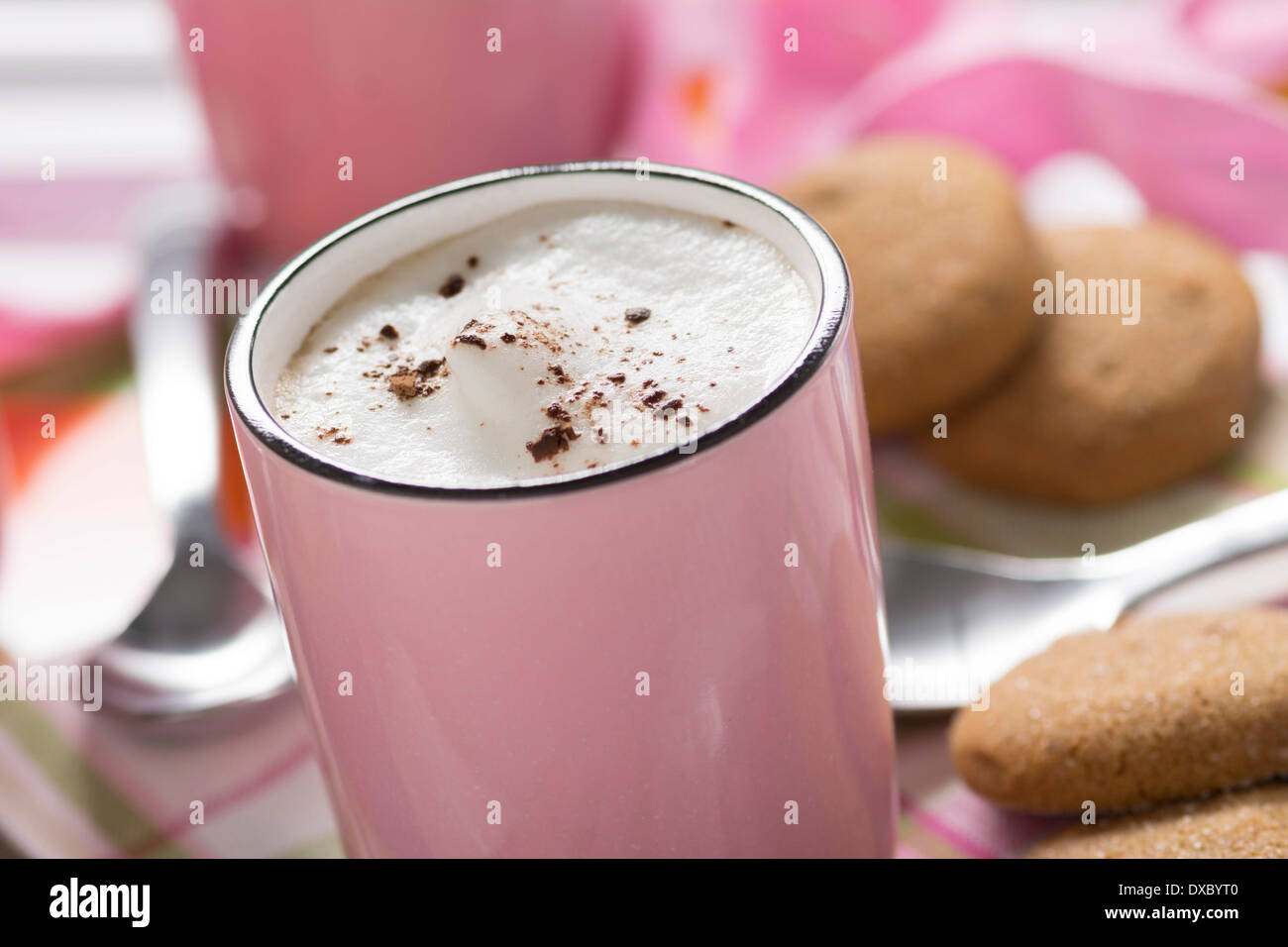 Cappuccino in rosa Tasse mit Kakao und Mandeln Milchschaum und Ingwer-Kekse Stockfoto