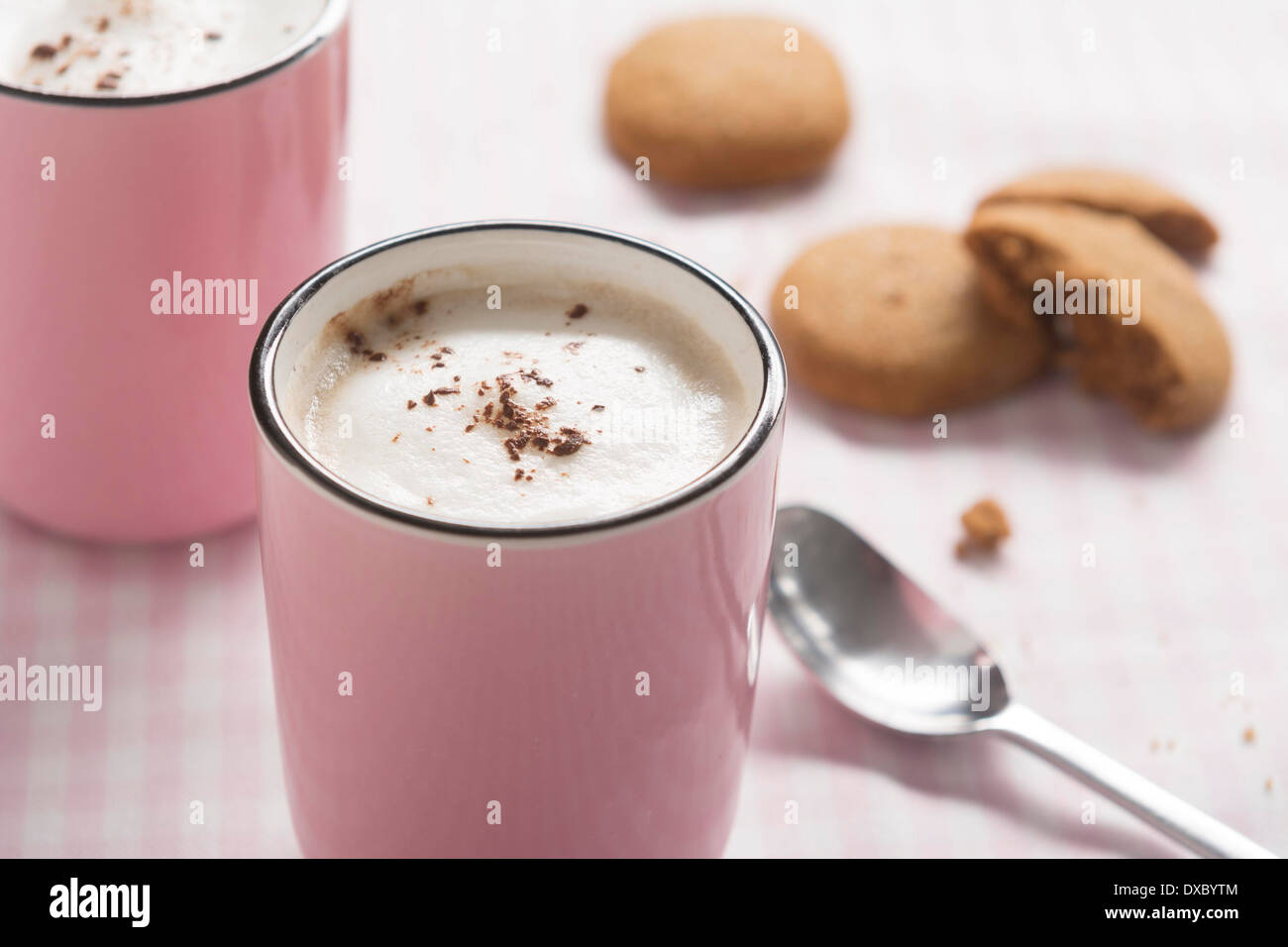 Cappuccino in rosa Tasse mit Kakao und Mandeln Milchschaum und Ingwer-Kekse Stockfoto