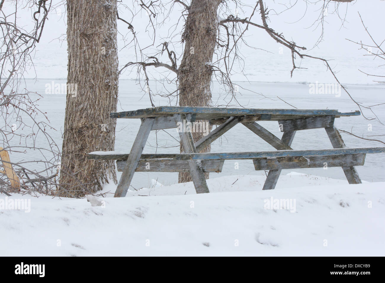 Eine leere Picknick-Tisch auf einer verschneiten Anhöhe mit Blick auf einem zugefrorenen See. Stockfoto