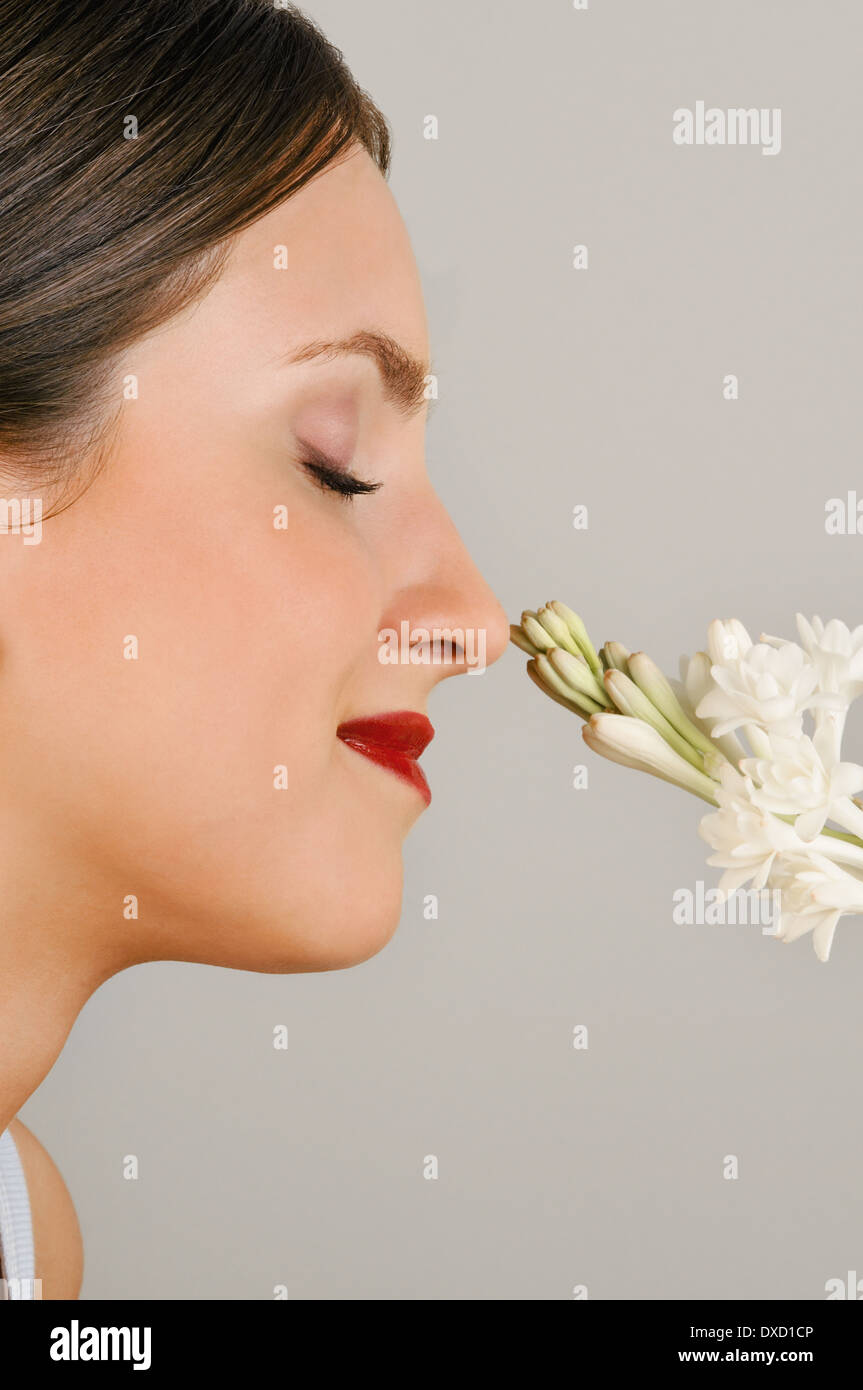 Weibliche junge Erwachsene riechen eine Blume Stockfoto