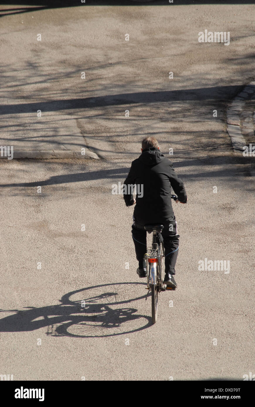 Ein Mann, der ganz in schwarz gekleidet ist und ein Fahrrad fährt. Stockfoto