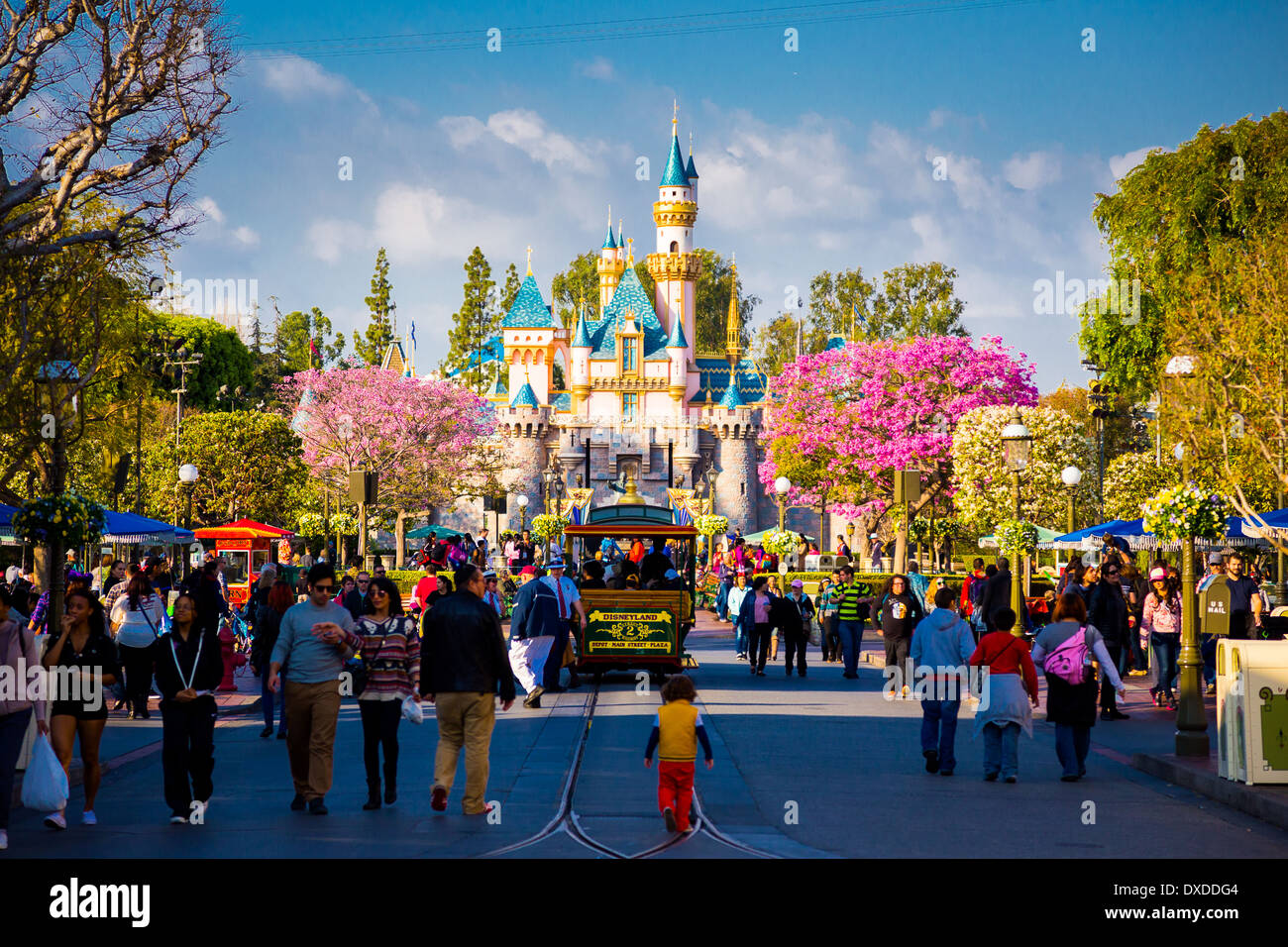 Disneyland Main Street überfüllt mit Gästen und eine Straßenbahn-Auto auf der Straße in Richtung der berühmten Rosa Schloss. Stockfoto