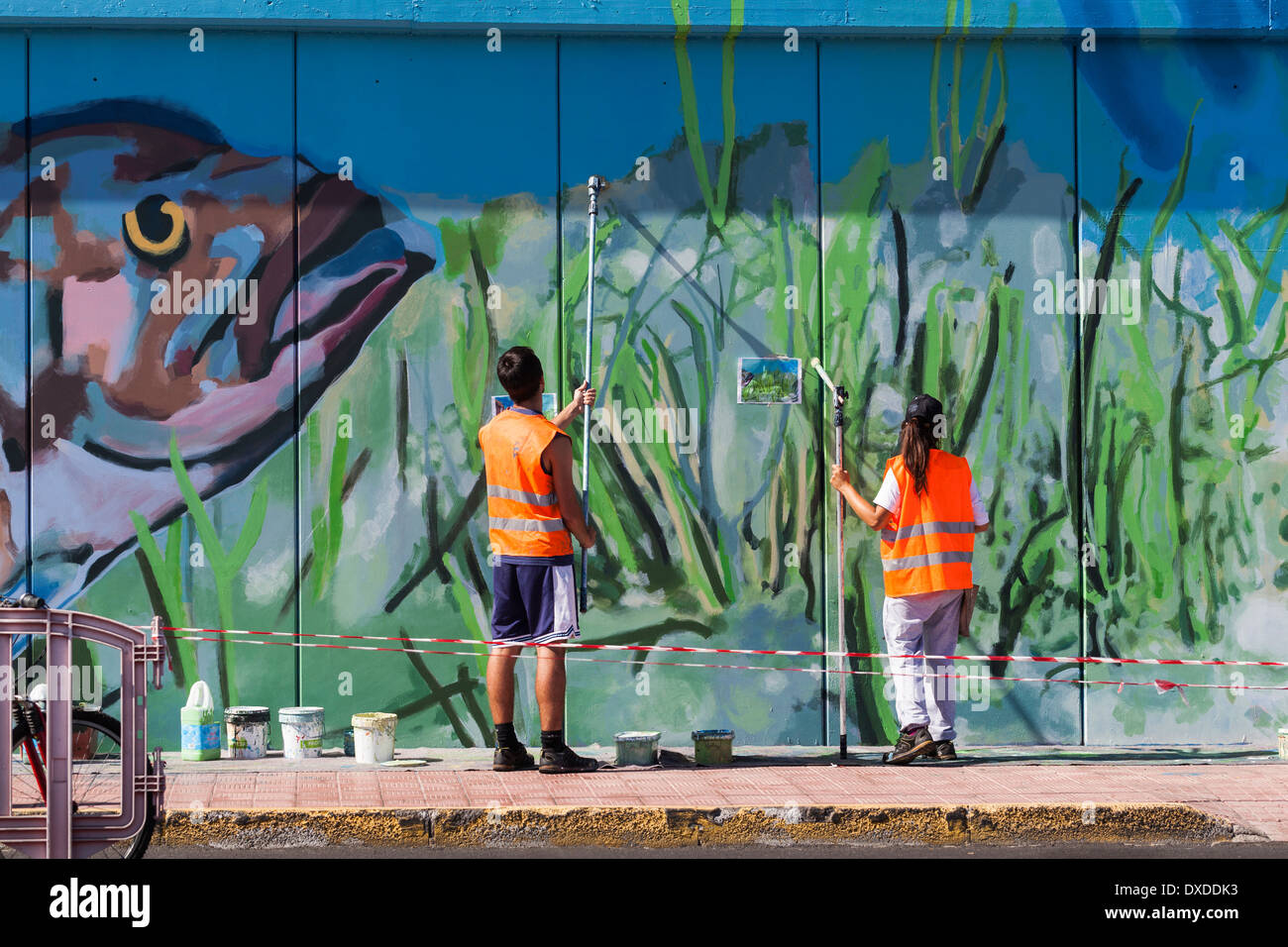 Kunststudenten malen ein Wandbild an der Hafenmauer in Los Cristianos-Teneriffa-Kanarische Inseln-Spanien Stockfoto