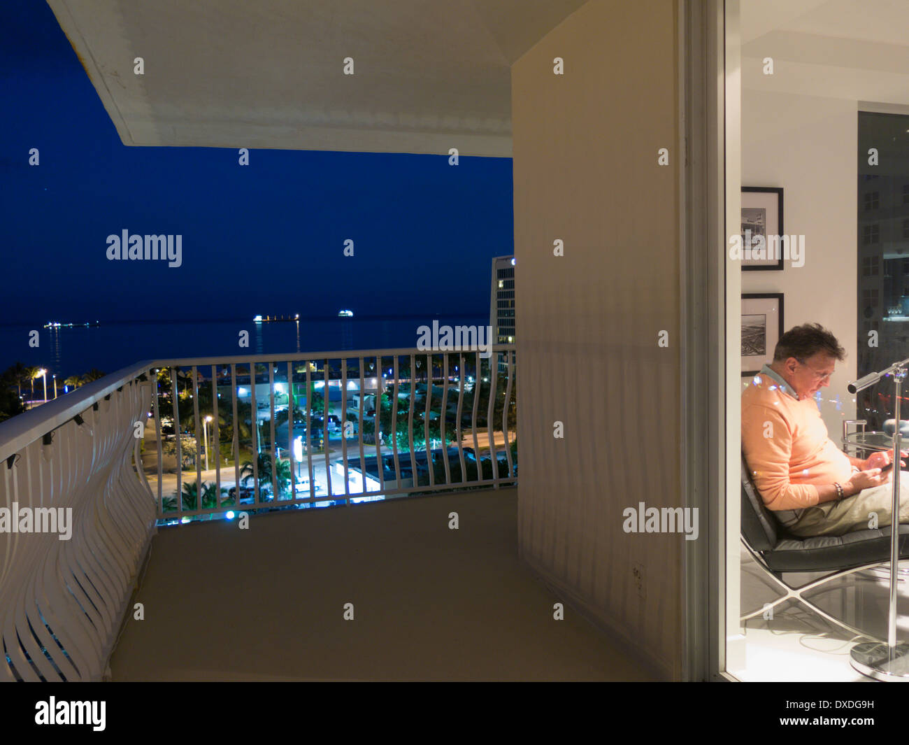 Reifer Mann Lesung in Luxus-Showcase-Eigentumswohnung, Blick vom Balkon in der Abenddämmerung, Fort Lauderdale, FL, USA Stockfoto