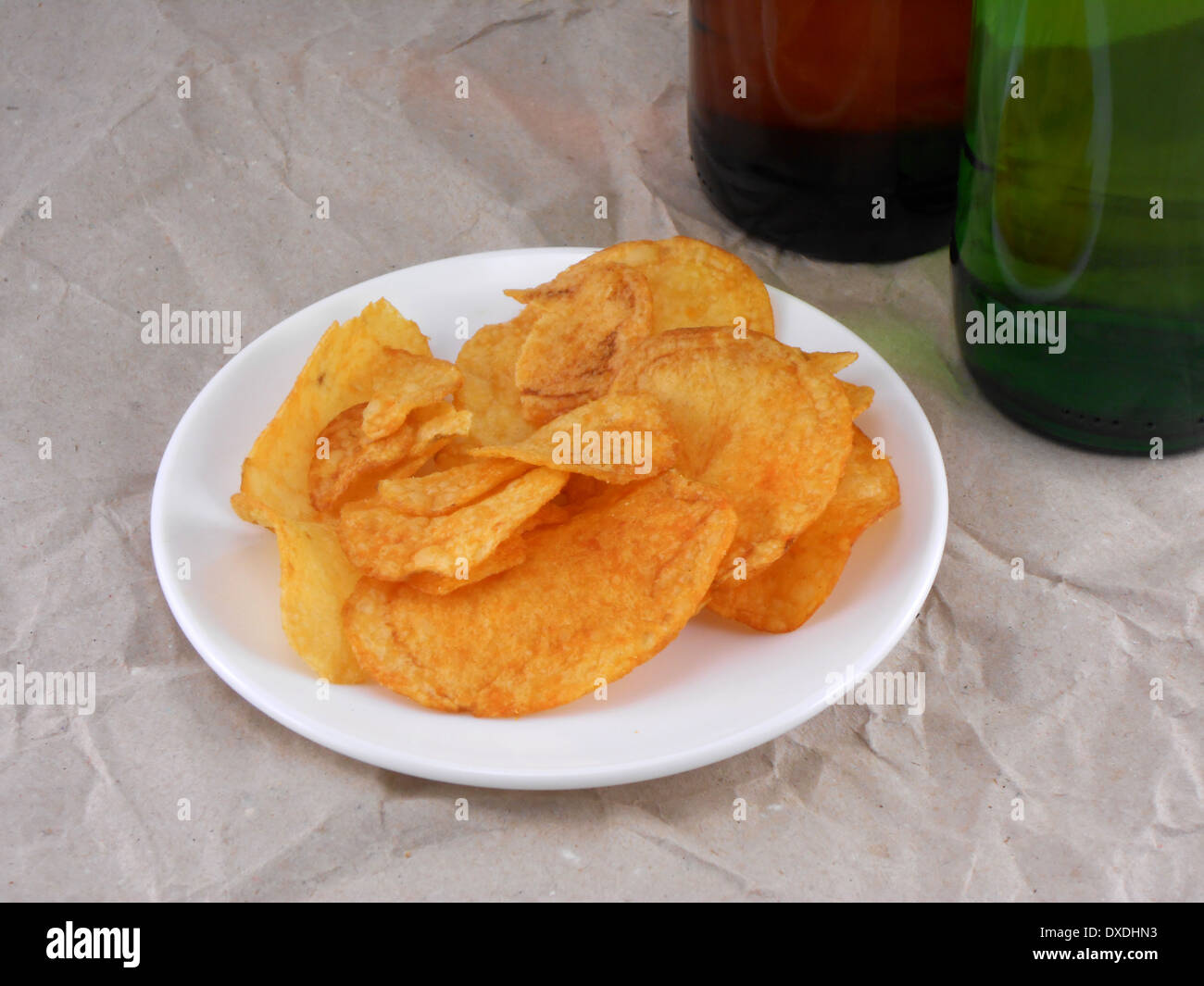 Bierflasche und Kartoffelchips auf weißen Teller Stockfoto