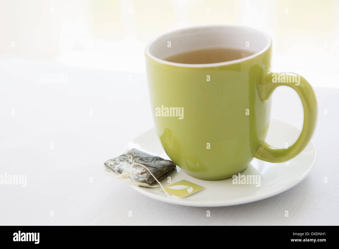 Verwendet Teebeutel auf Untertasse mit Tasse Tee im grünen Becher, Studioaufnahme Stockfoto