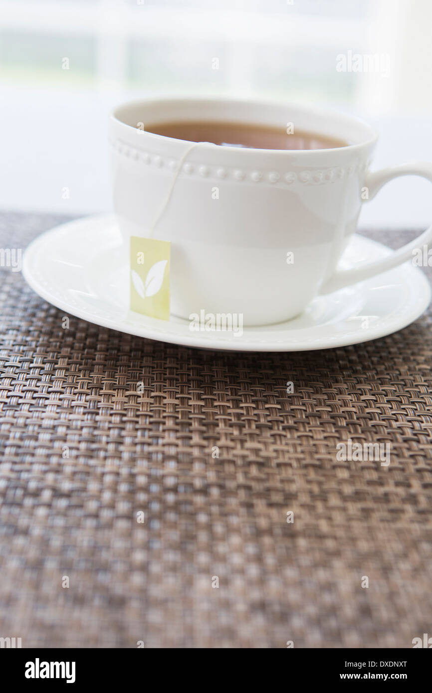 Tasse Tee in weißem Porzellantasse mit Untertasse und Teebeutel, Studio gedreht Stockfoto