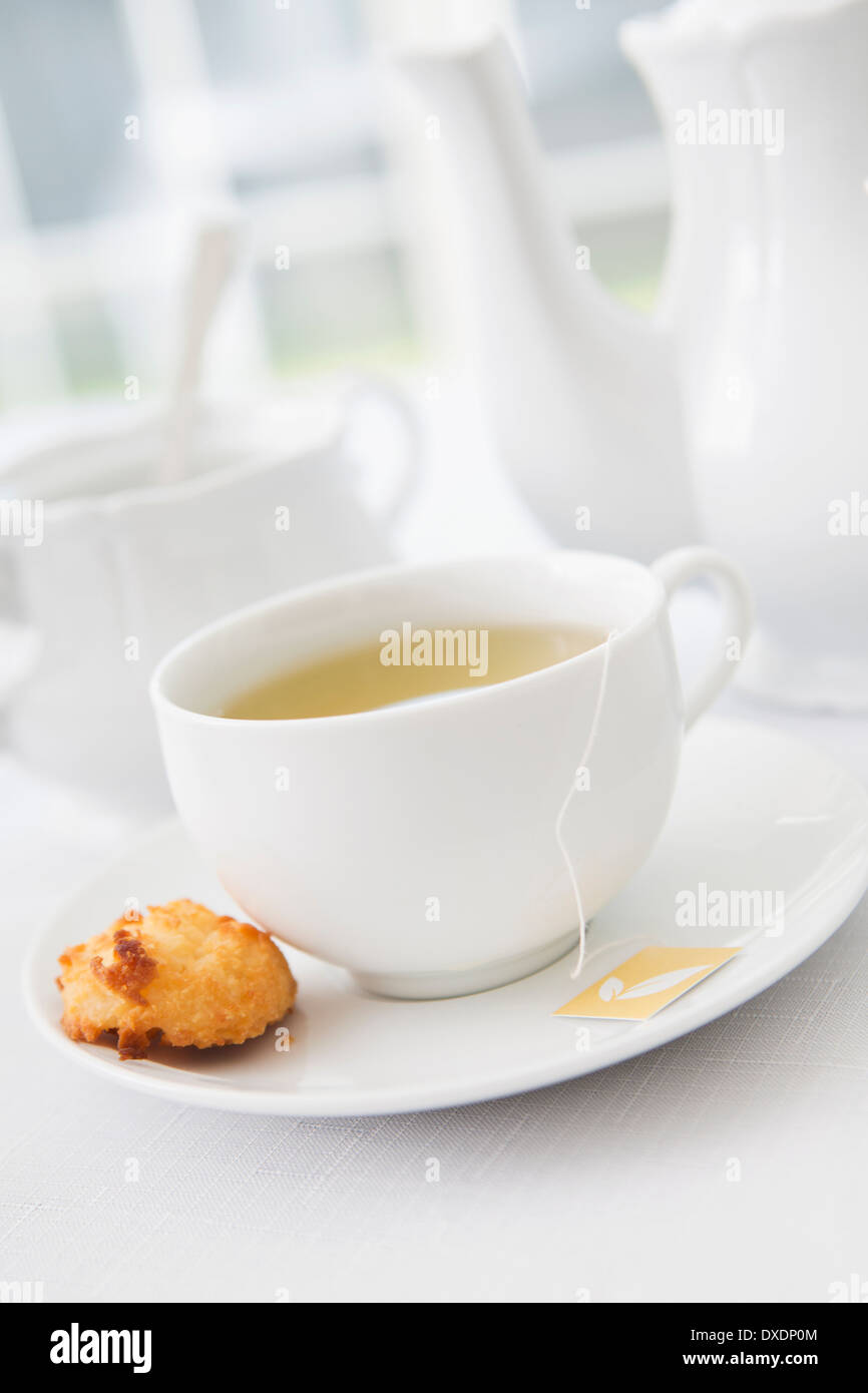 Tasse Tee in weißem Porzellan Teetasse mit Unterteller, Zuckerdose, Teekanne und Teller Kokosmakronen, Studio gedreht Stockfoto