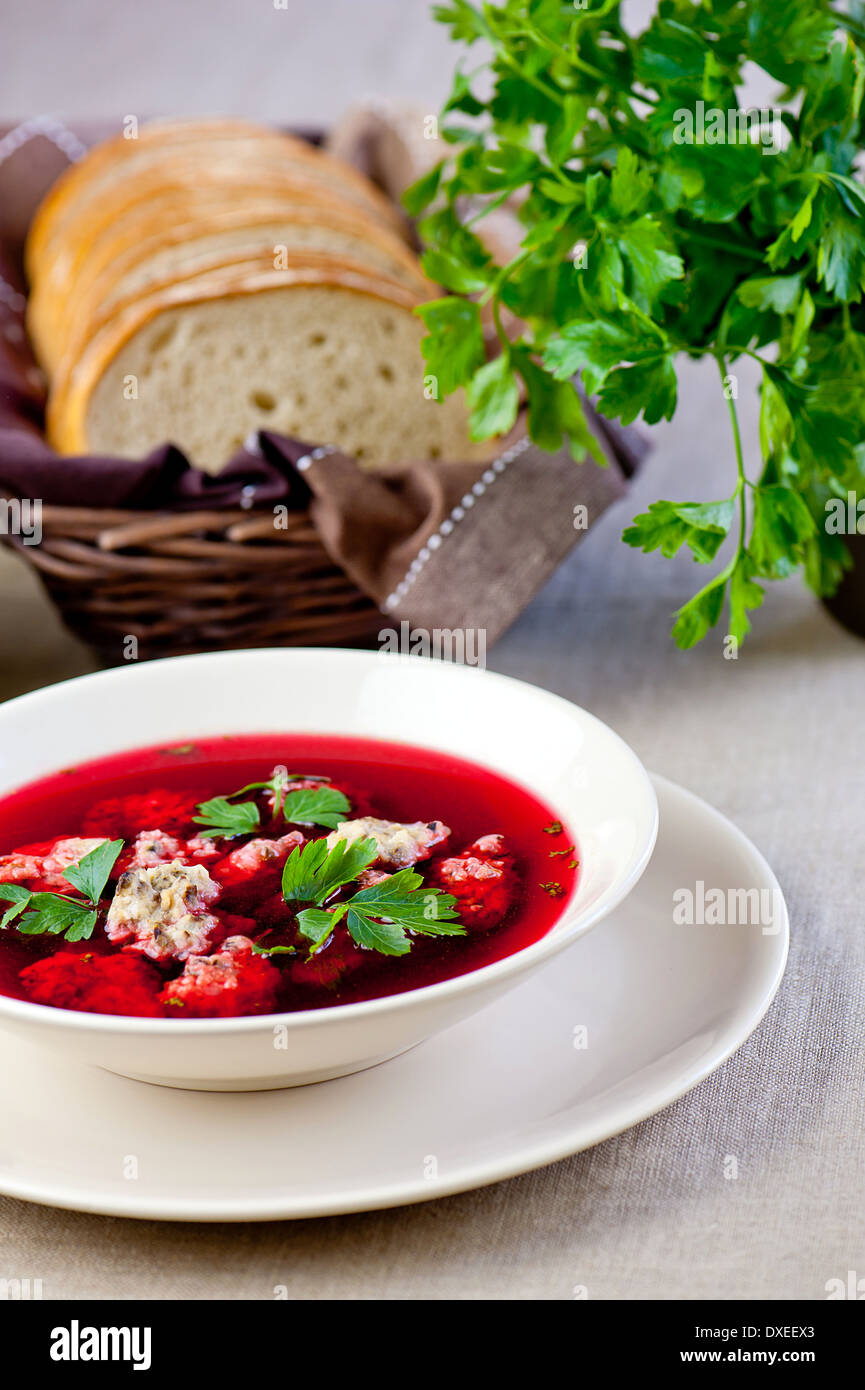 Teller mit roten Borschtsch. Brot und Petersilie im Hintergrund Stockfoto