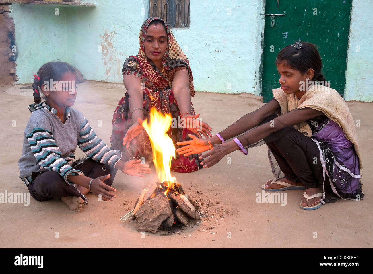 Indien, Uttar Pradesh, Agra, Frau und zwei Töchter Erwärmung ihre Hände neben ein kleines Feuer angeheizt durch Kuhmist und Bambus Stockfoto
