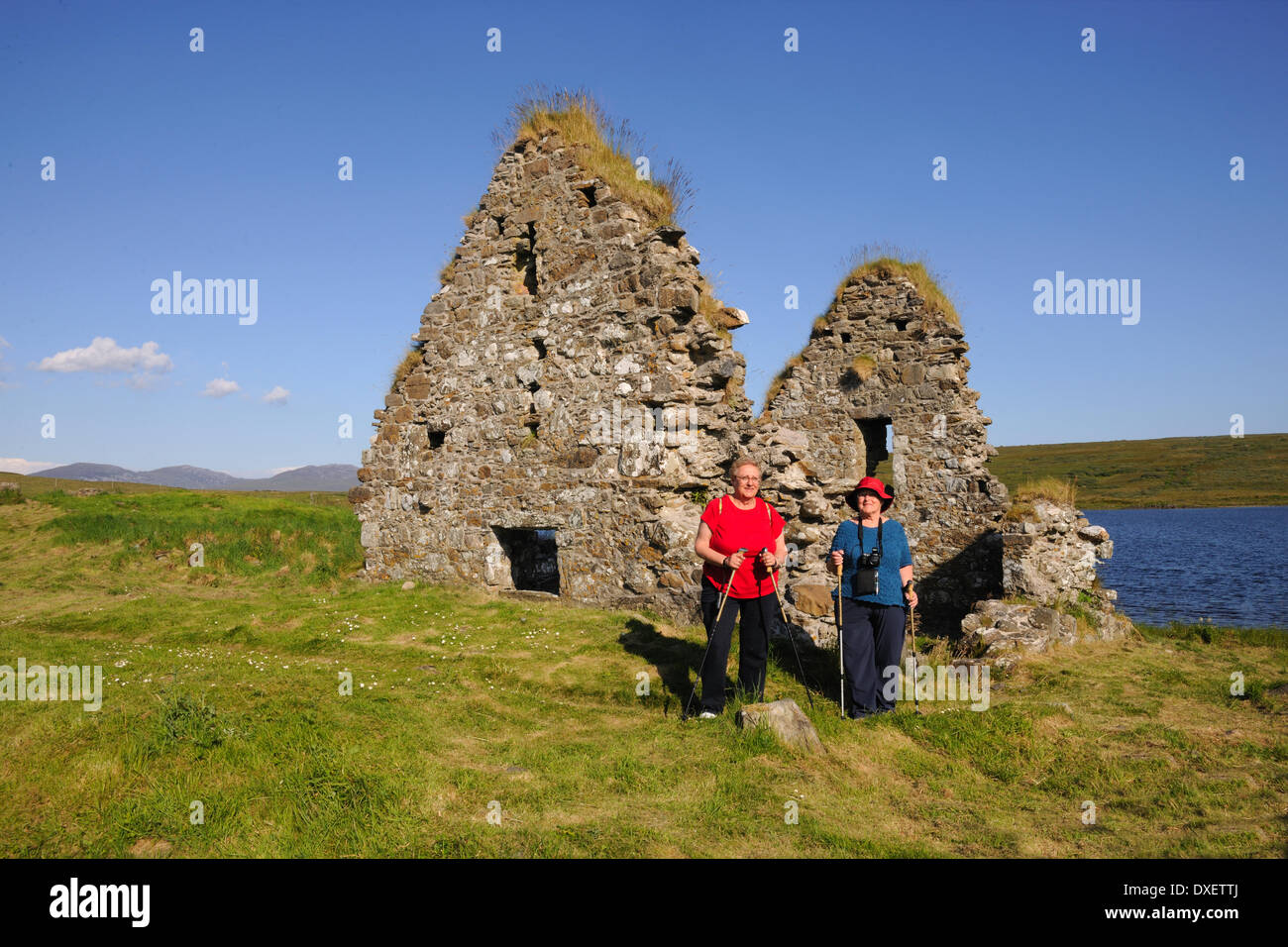 Zwei amerikanische Touristen bewundern die Ruinen auf Eilean Mor, Loch Finlaggan, Islay Stockfoto