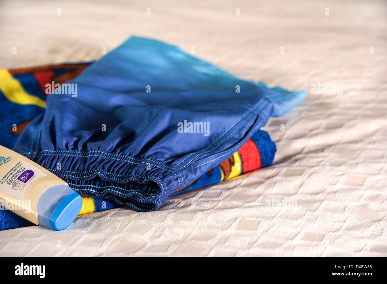 Badeshorts, Strandtuch und hohem Lichtschutzfaktor Sonnencreme. Stockfoto