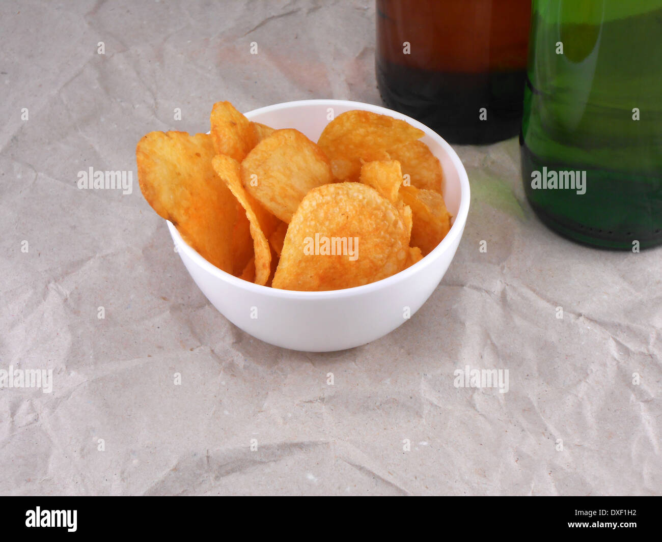 Bierflasche und Kartoffelchips auf weißen Teller Stockfoto