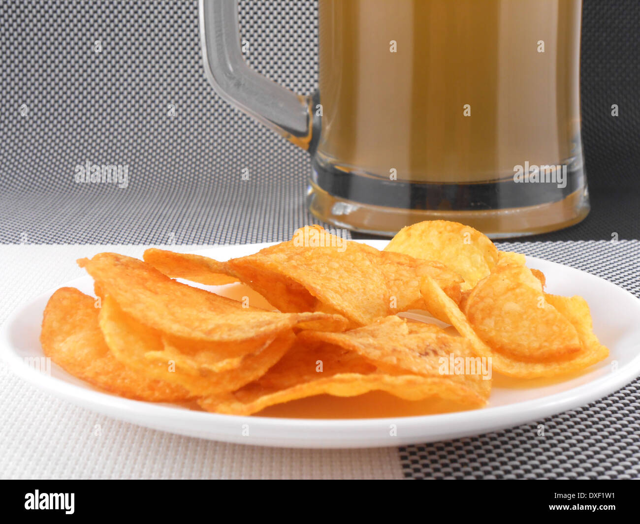 Tasse frisch gezapftes Bier und Platte mit Haufen Pommes frites Stockfoto