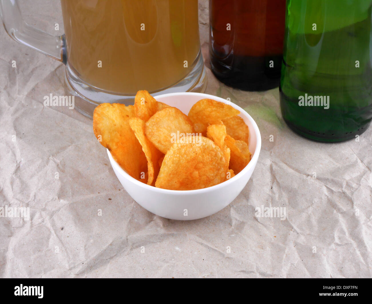 Bierflasche und Kartoffelchips auf weißen Teller Stockfoto