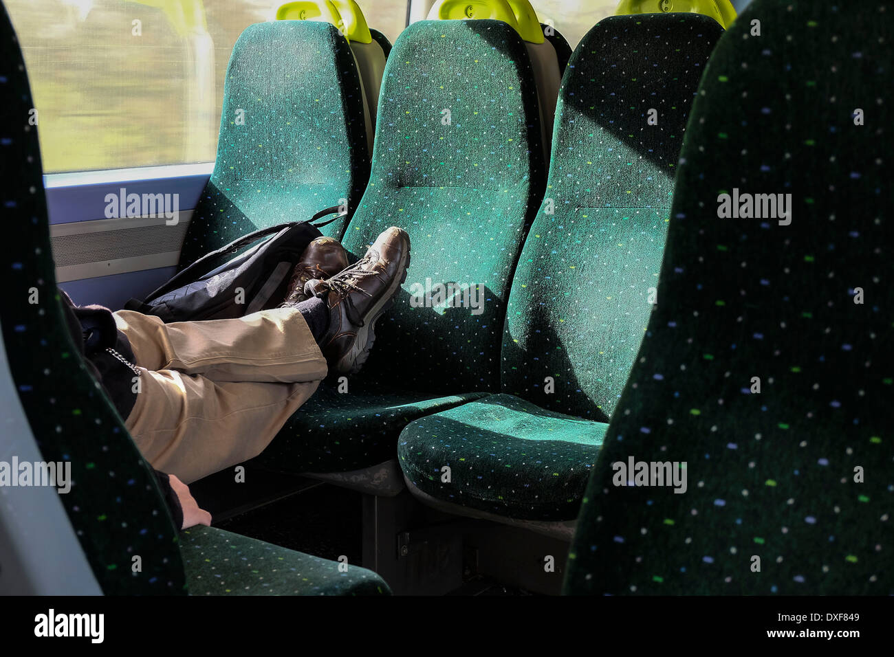 Ein Mann mit seinen Füßen auf sitzen in einem Zug. Stockfoto