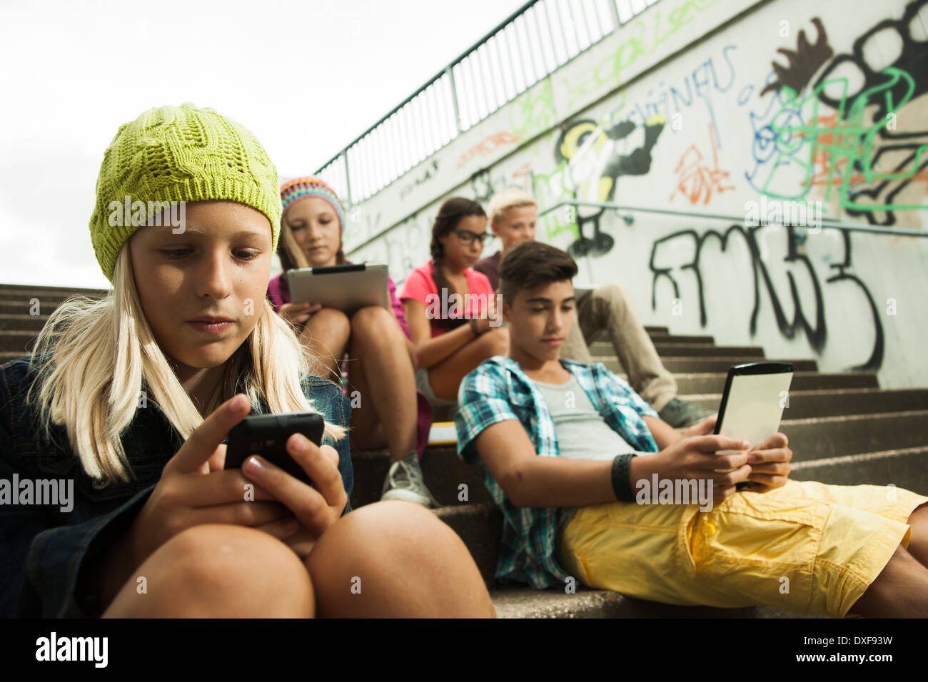 Gruppe von Kindern auf Treppen im Freien, sitzend mit Tablet-PCs und Smartphones, Deutschland Stockfoto
