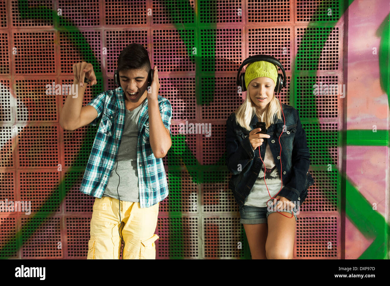 Kinder stehen neben Wand im Freien, tragen von Kopfhörern und Musik hören, Deutschland Stockfoto