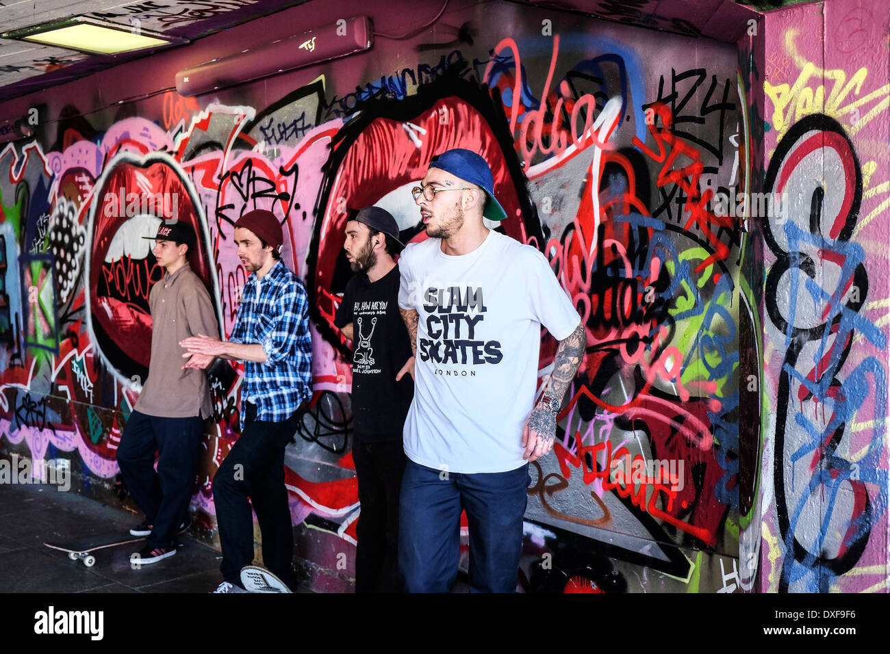 Skateboarder stehen gegen eine Graffiti bedeckt Wand an der South Bank Skateboard-Park in London. Stockfoto