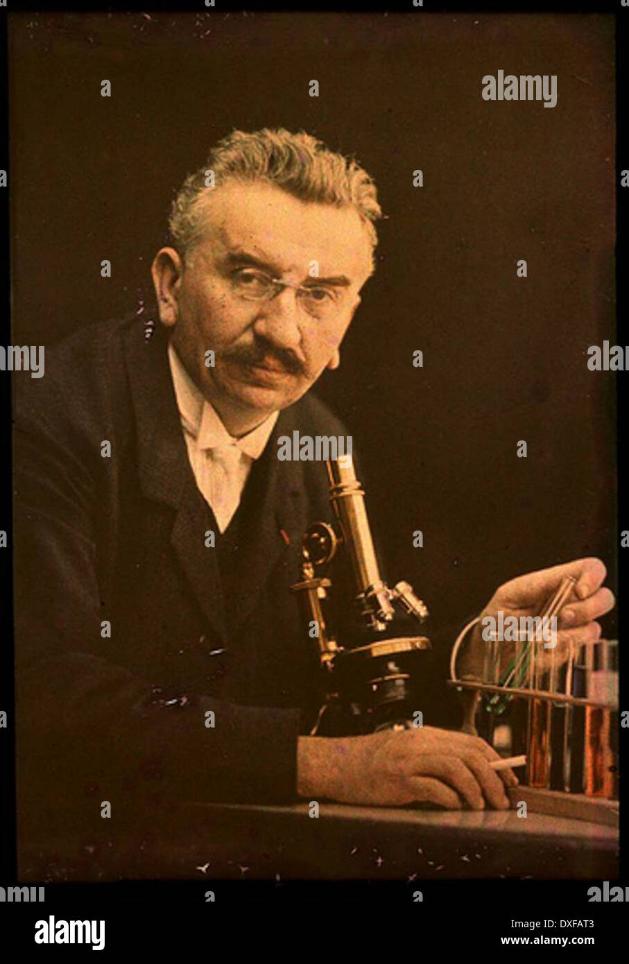 Dieses historische Foto zeigt Louis Lumière, den französischen Erfinder und Mitschöpfer des Kinos, mit einem Mikroskop und Reagenzgläsern, die möglicherweise mit seinen frühen wissenschaftlichen Untersuchungen vor seiner Filmarbeit in Verbindung gebracht wurden. Stockfoto