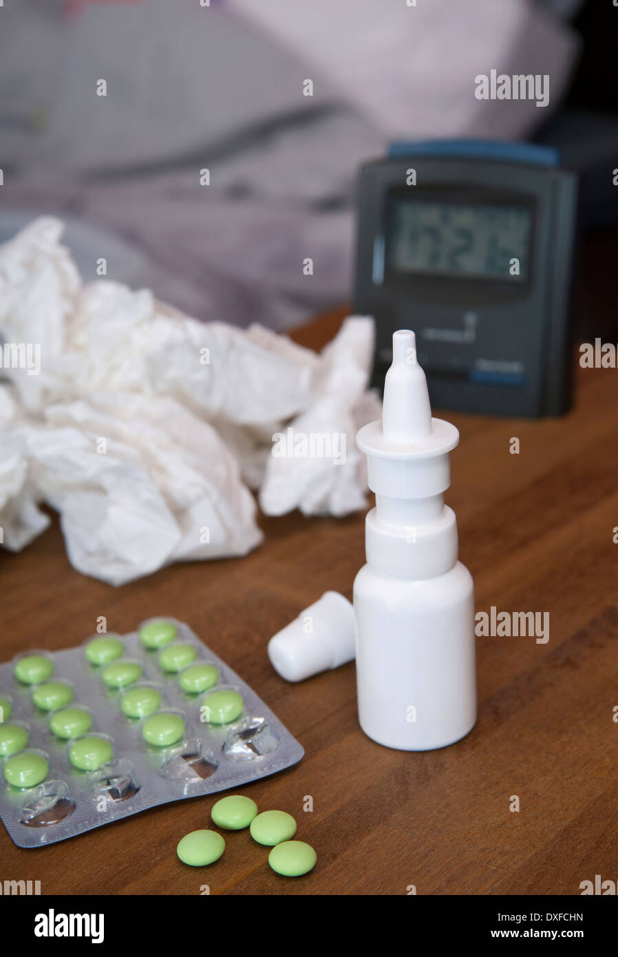 Medikamente und zerknitterte Kosmetiktücher und Alarm clock auf Nachttisch, Studio gedreht Stockfoto