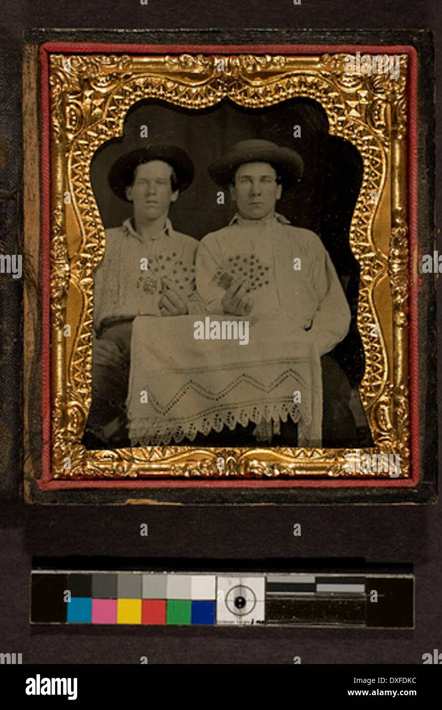 Dieses Vintage-Foto zeigt zwei Männer, die an einem Tisch sitzen und jeweils eine Hand von fünf Karten zeigen. Das Bild stammt aus einer vergangenen Zeit und zeigt einen Moment in der Zeit, in dem Kartenspiele beliebte Freizeitbeschäftigungen waren. Stockfoto