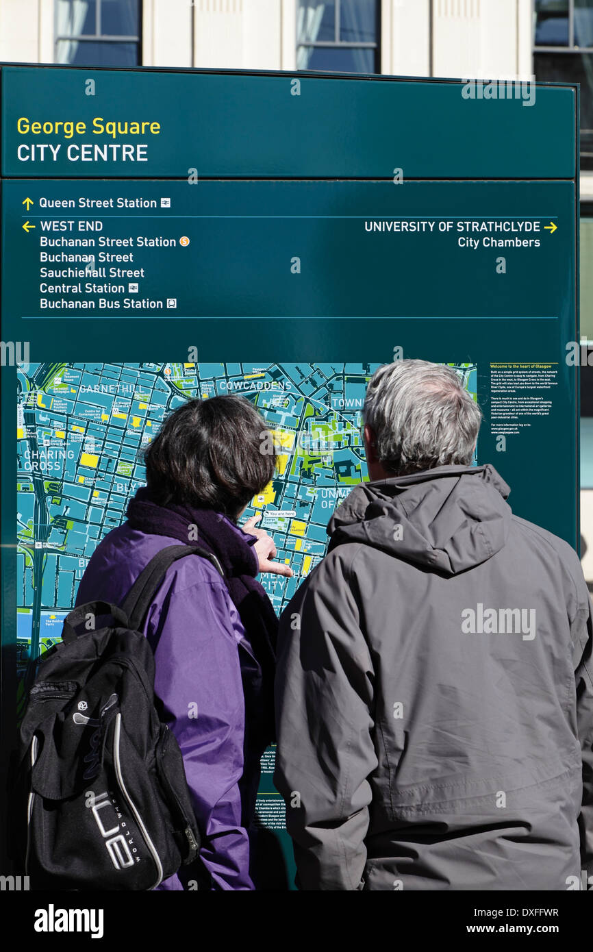 Zwei Touristen, die sich einen öffentlichen Stadtplan von Glasgow im Stadtzentrum ansehen, George Square, Glasgow, Schottland, Großbritannien Stockfoto