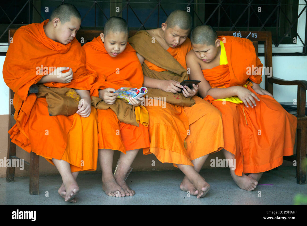 Junge Mönche sitzen zusammen lesen und teilen ein Magazin und Gerät Stockfoto