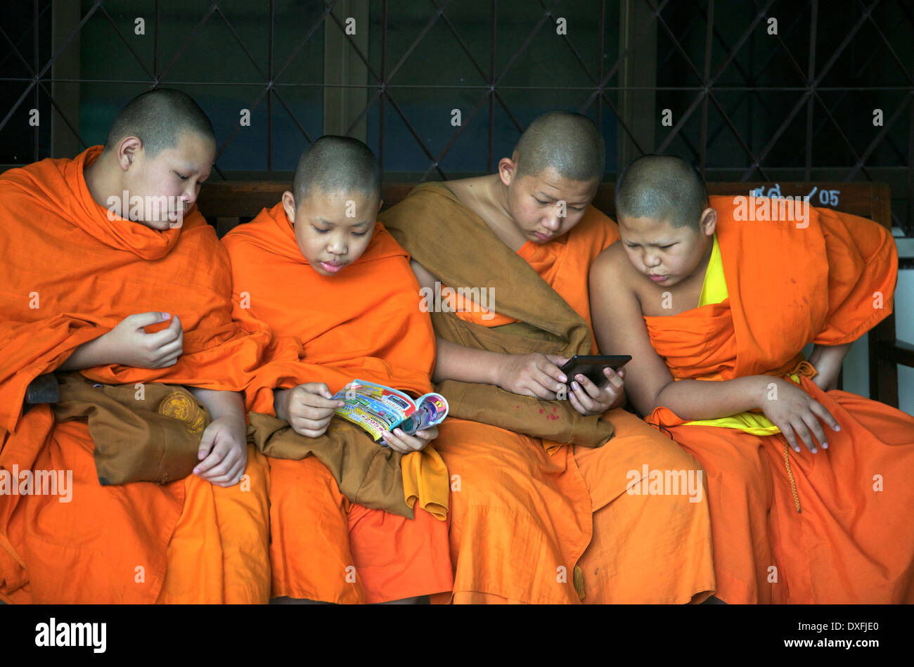Junge Mönche sitzen zusammen auf einer Bank Stockfoto