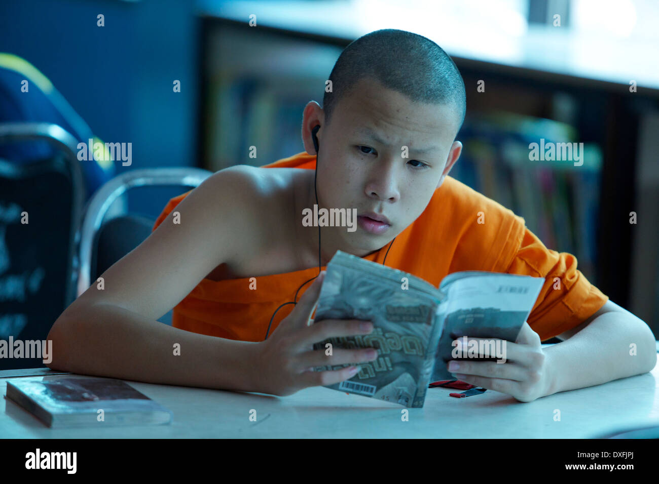 Junger Mönch ein Buch zu lesen, während Sie Musik hören Stockfoto