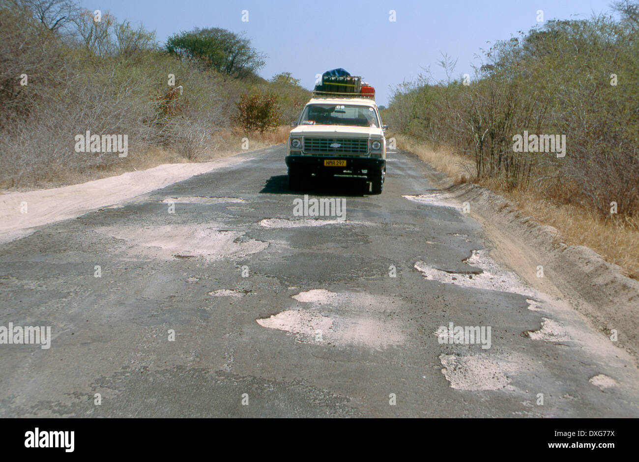 Schlechte Schlaglöcher auf der geteerten Straße in der Nähe von Livingstone, Sambia Stockfoto