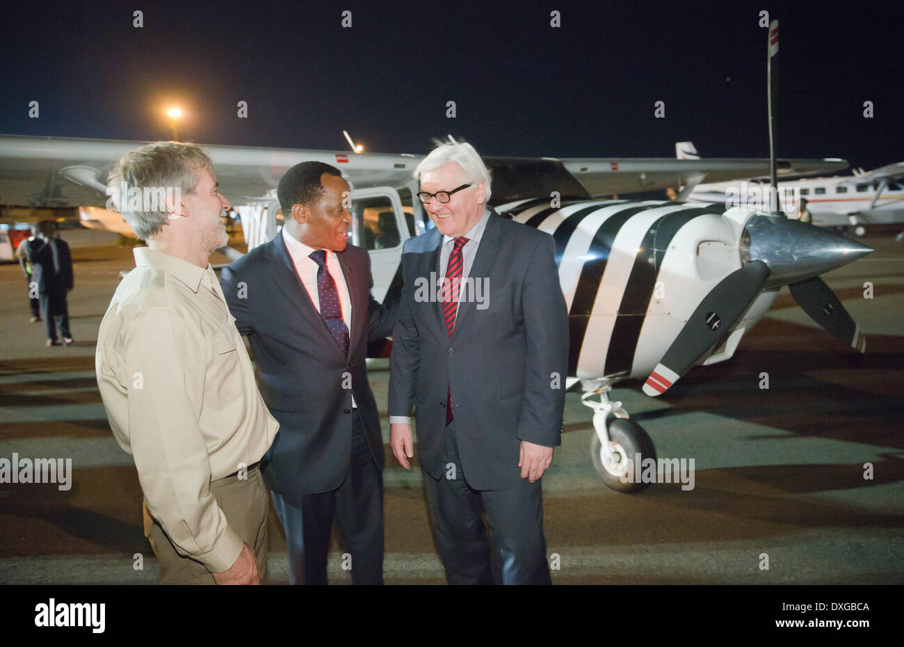 Daressalam, Tansania, Deutschland. 25. März 2014. Der deutsche Außenminister Frank-Walter Steinmeier (SPD, R) steht neben Lazaro Nyalandu (C), Minister für Naturschutz und Tourismus, und Christof Schenck, Manager der Frankfrut Zoologischen Gesellschaft vor einem Flugzeug gemalt mit Zebrastreifen nach hatte Ente "Flugzeuge von Bernhard Grzimek nach einen Vortrag über Naturschutz und Wilderei in Daressalam, Tansania, Deutschland, 25. März 2014. Foto: Michael Kappeler/Dpa/Alamy Live News Stockfoto