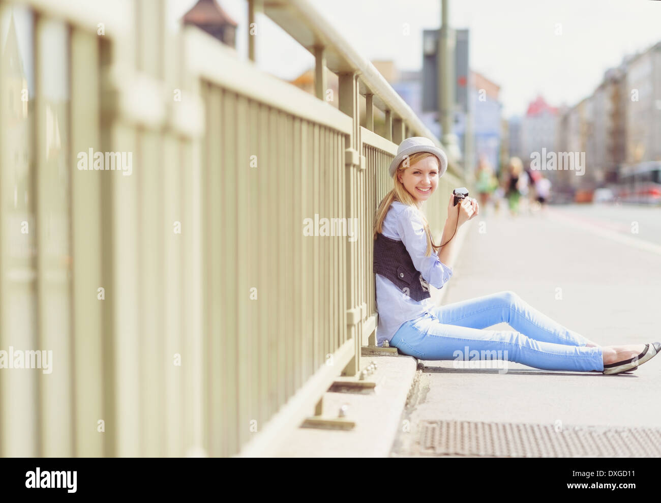 Junge Hipster sitzen auf Stadtstraße mit Retro-Foto-Kamera Stockfoto