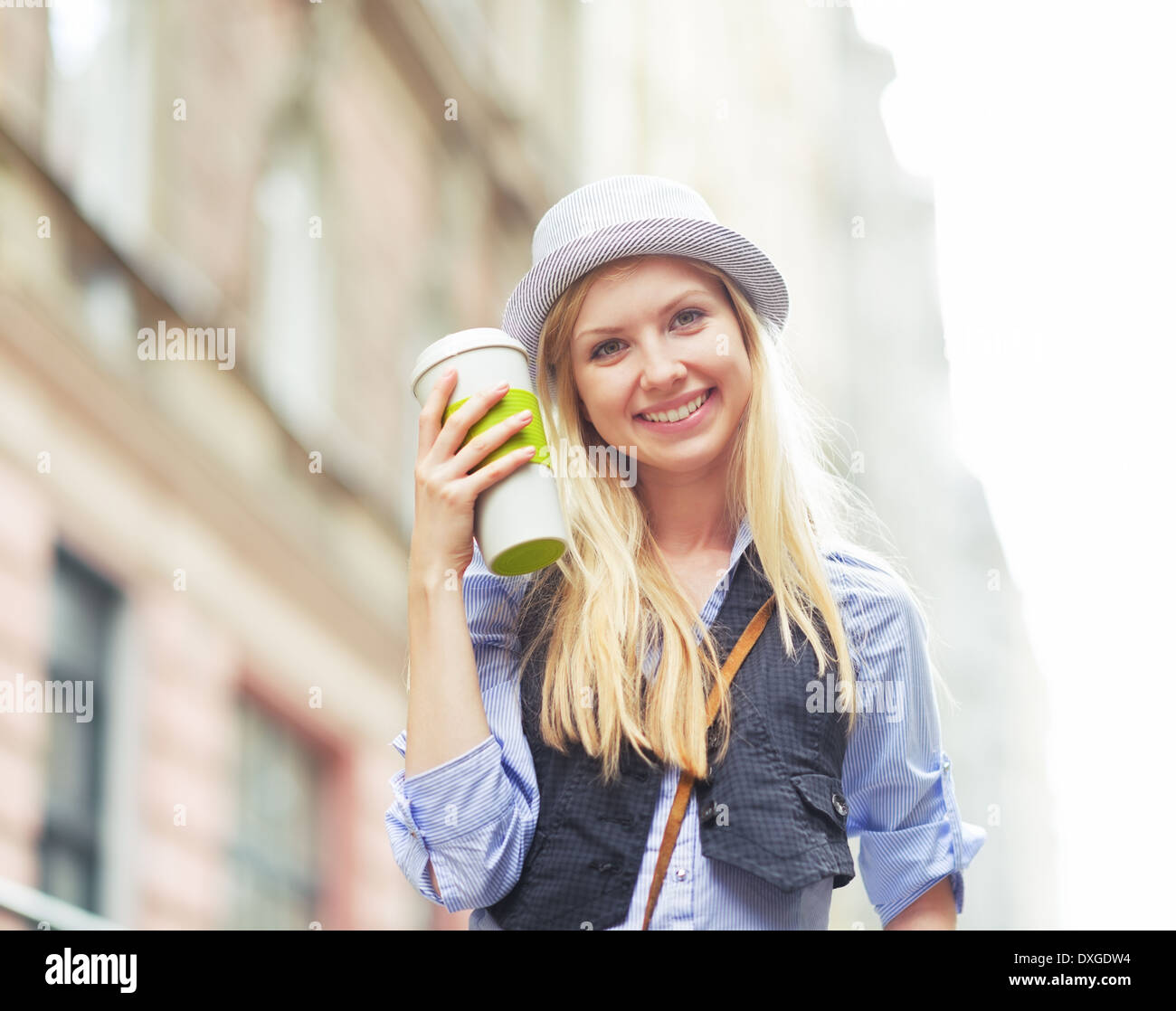 Glückliche junge Hipster mit Tasse Heißgetränk in der Stadt Stockfoto