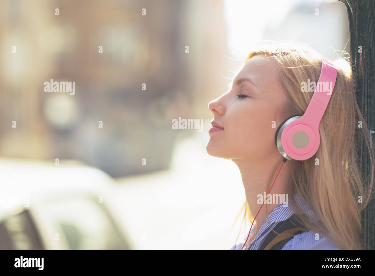 Junge Frau hören von Musik im Kopfhörer in der Stadt Stockfoto