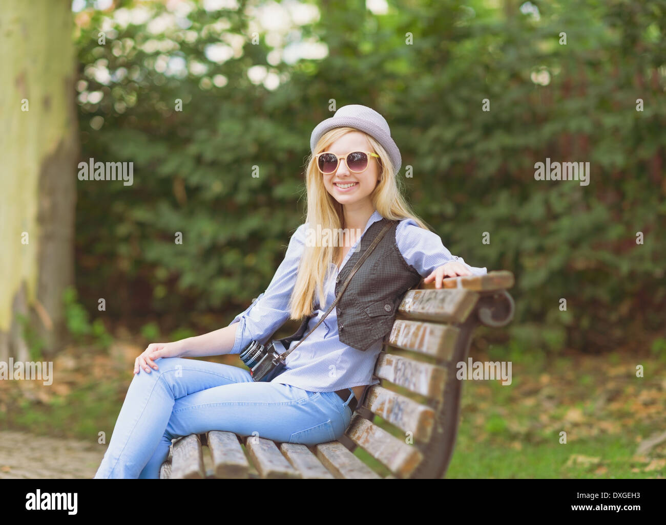 Junge Hipster sitzt auf der Bank im park Stockfoto