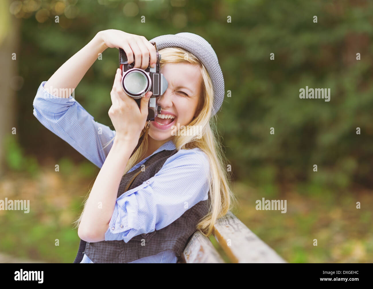 Junge Hipster nehmen Foto mit Retro-Foto-Kamera sitzt auf der Bank im park Stockfoto