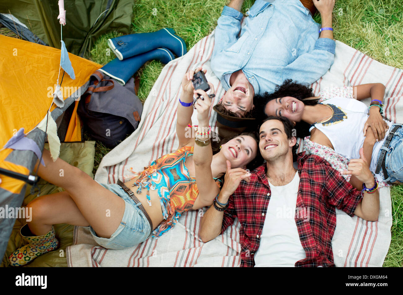 Freunde unter Selbstporträt auf Decke vor Zelt Musik Festival Stockfoto