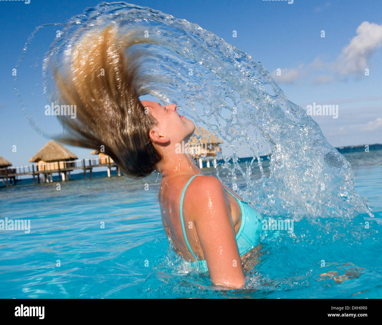 Mädchen im Bikini wirft ihr Haar zurück in eine Dusche von Spray in einem  tropischen Luxus-Resort in Französisch-Polynesien Stockfotografie - Alamy