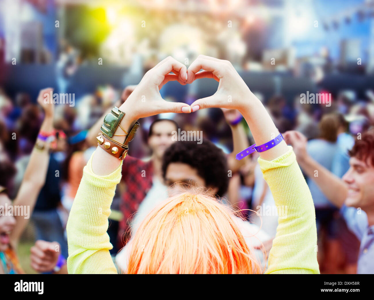 Frau bildet Herzform mit Händen am Musikfestival Stockfoto