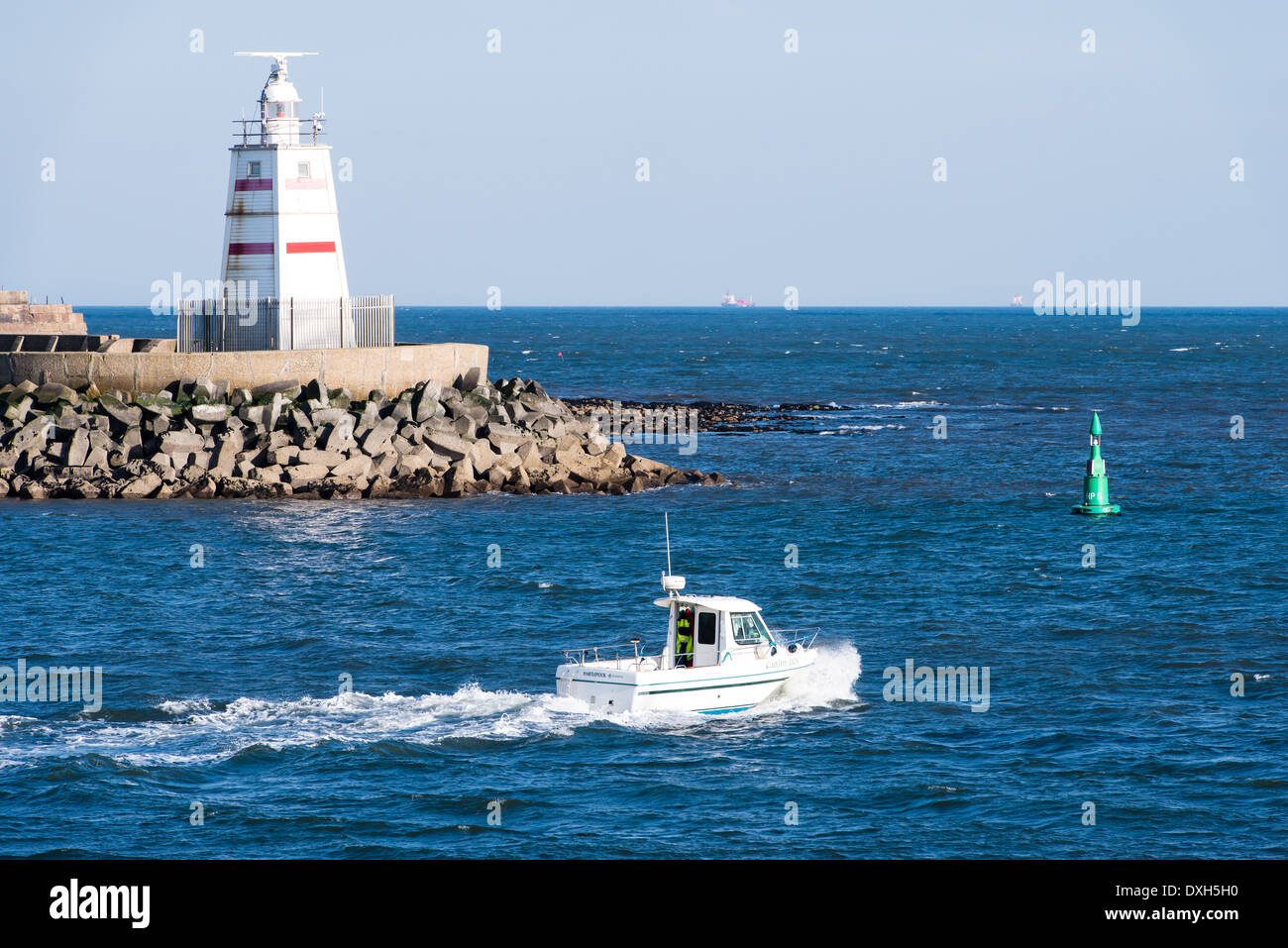 Ein kleines weißes Boot geht einen Leuchtturm, als es heraus zum Meer vorbei an dem Pilot-Pier in Hartlepool, Nord-Ost-England leitet. Stockfoto