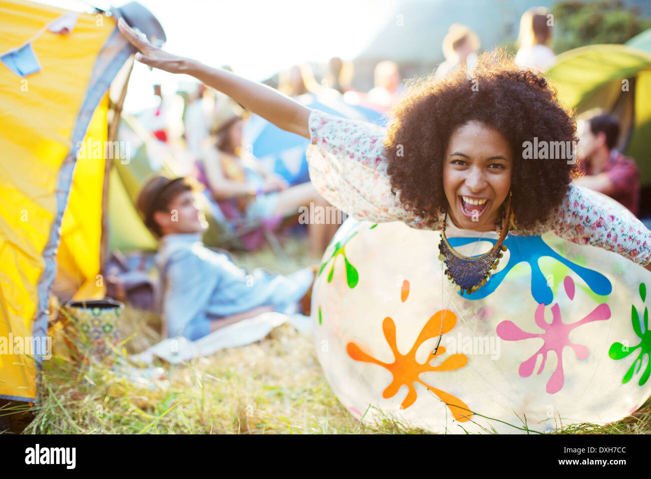 Portrait von verspielten Frau Handauflegen aufblasbarer Stuhl außerhalb Zelte beim Musikfestival Stockfoto