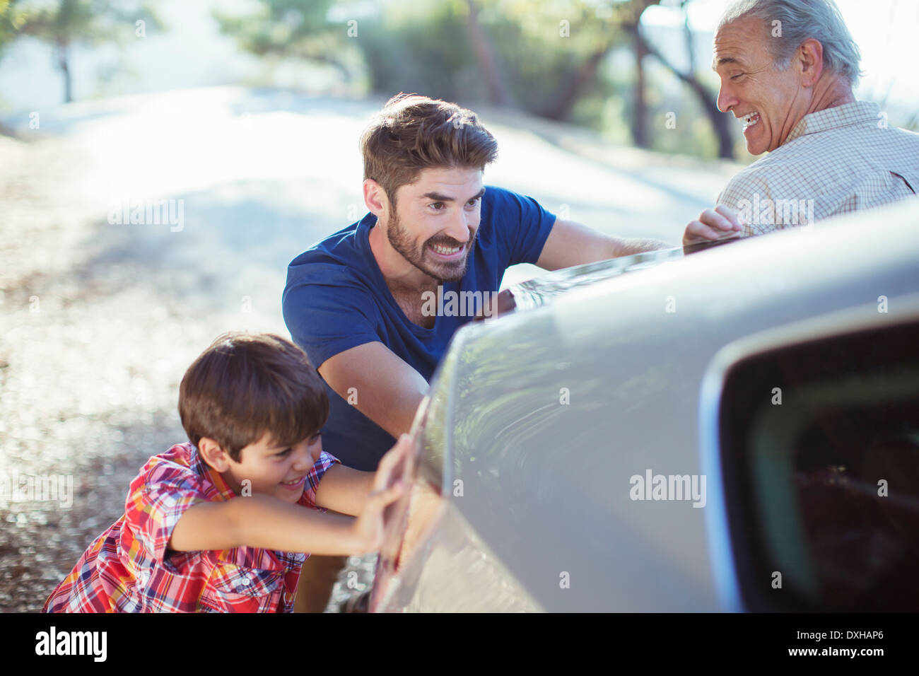 Generationsübergreifende Männer schieben Auto am Straßenrand Stockfoto