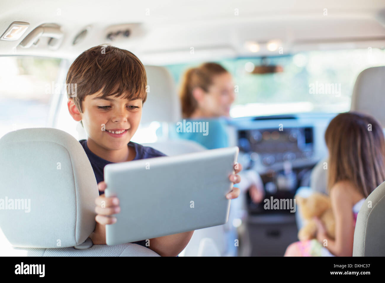 Fröhlicher Junge mit digital-Tablette im Rücksitz des Wagens Stockfoto