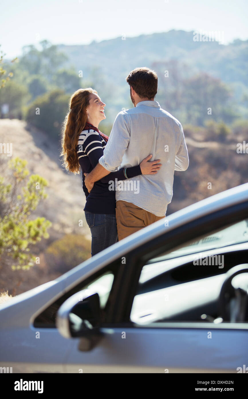 Glückliches Paar umarmt am Straßenrand außerhalb Auto Stockfoto